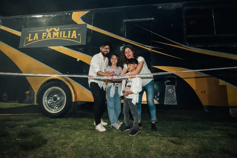 La familia fundadora corta la cinta de inauguración, de noche, frente al colectivo negro con franjas doradas